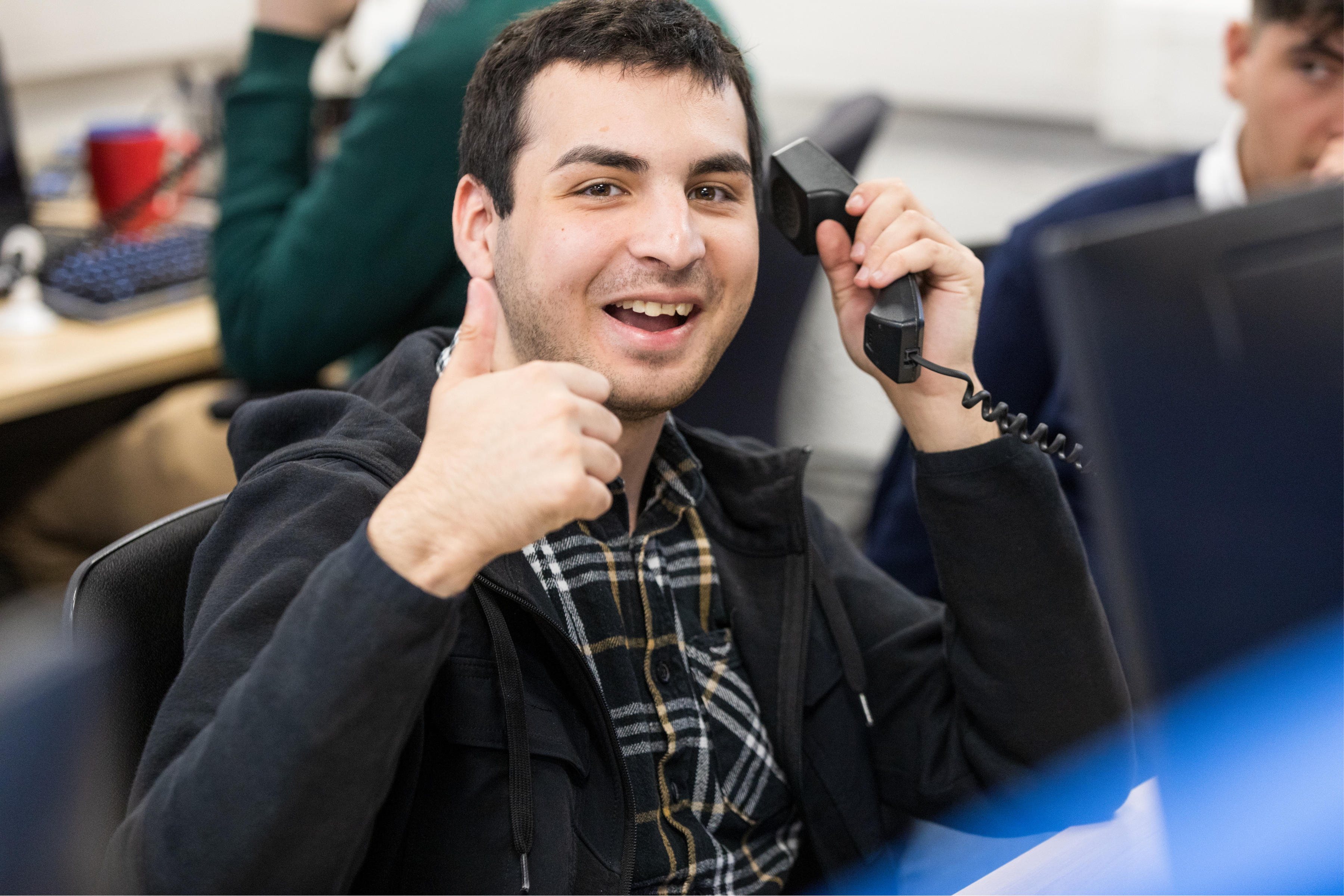 Mikail smiling with a thumbs up whils holding the phone